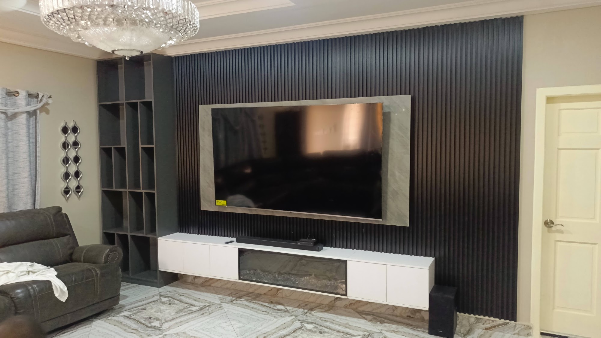 TV wall with dark vertical panels, wood surround and low white cabinetry