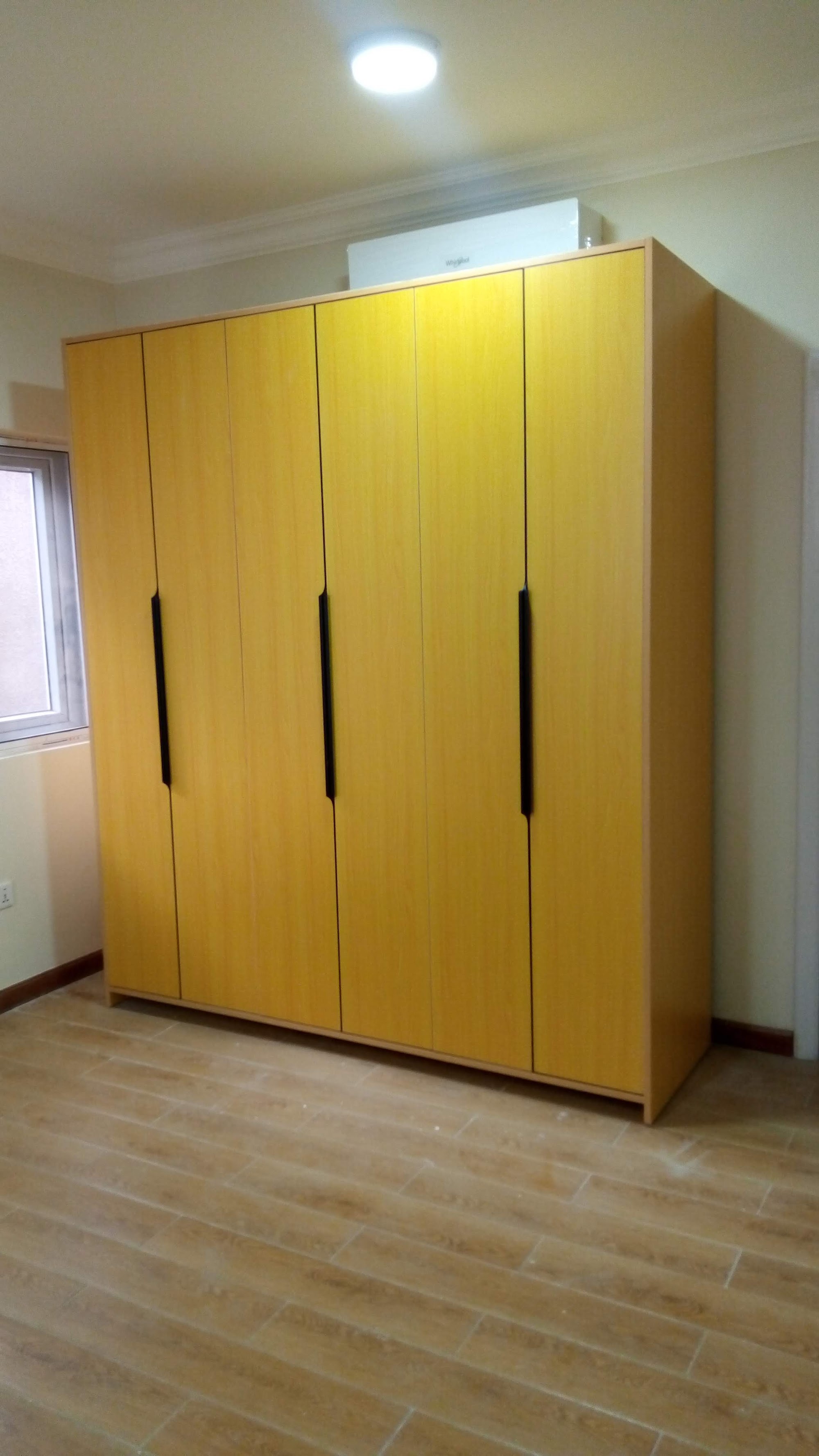 Wood-finish wardrobe with tall doors and dark handles
